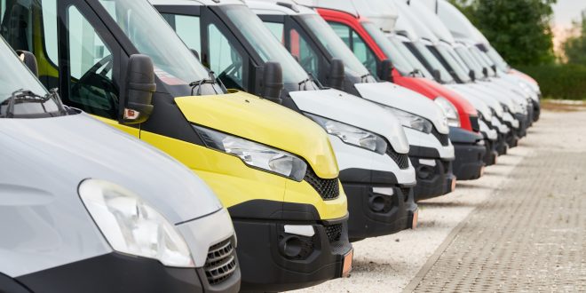 Fleet of commercial van trucks in row. Logistics and transportation service company